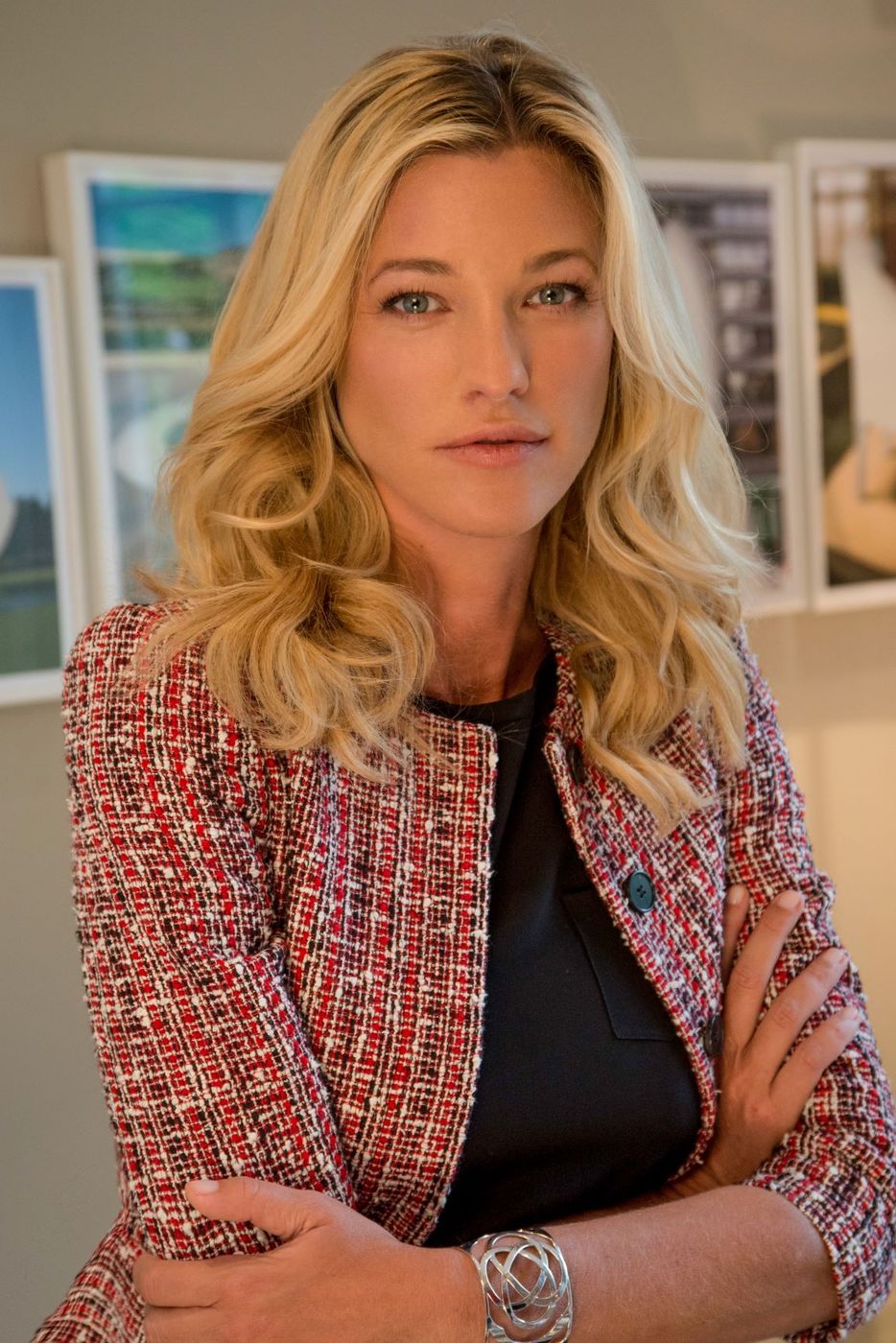 Nicole Junkermann in giacca di tweed a braccia conserte, con alle spalle alcune stampe incorniciate appoggiate al muro